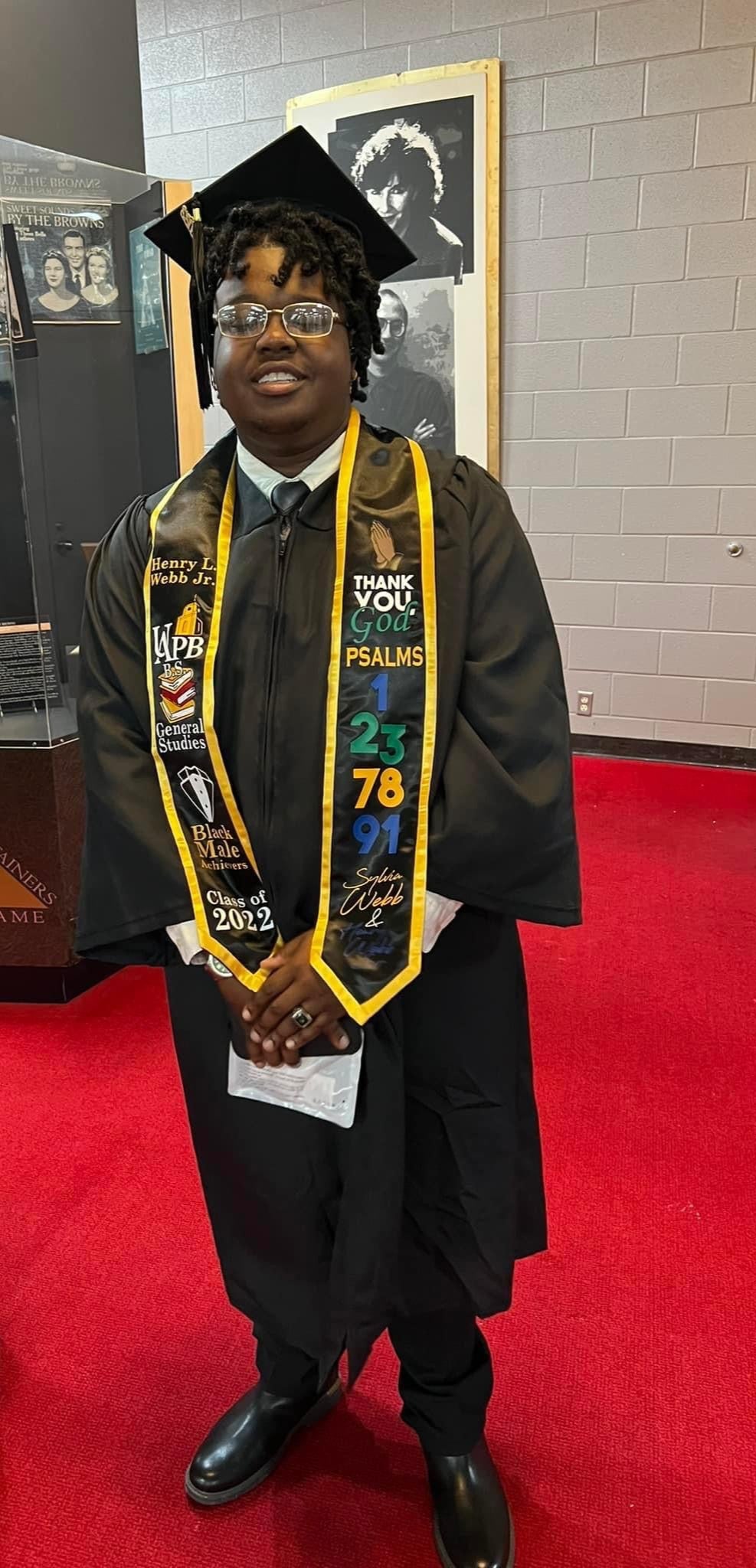 Graduate in cap and gown with a custom grastole on a red carpet