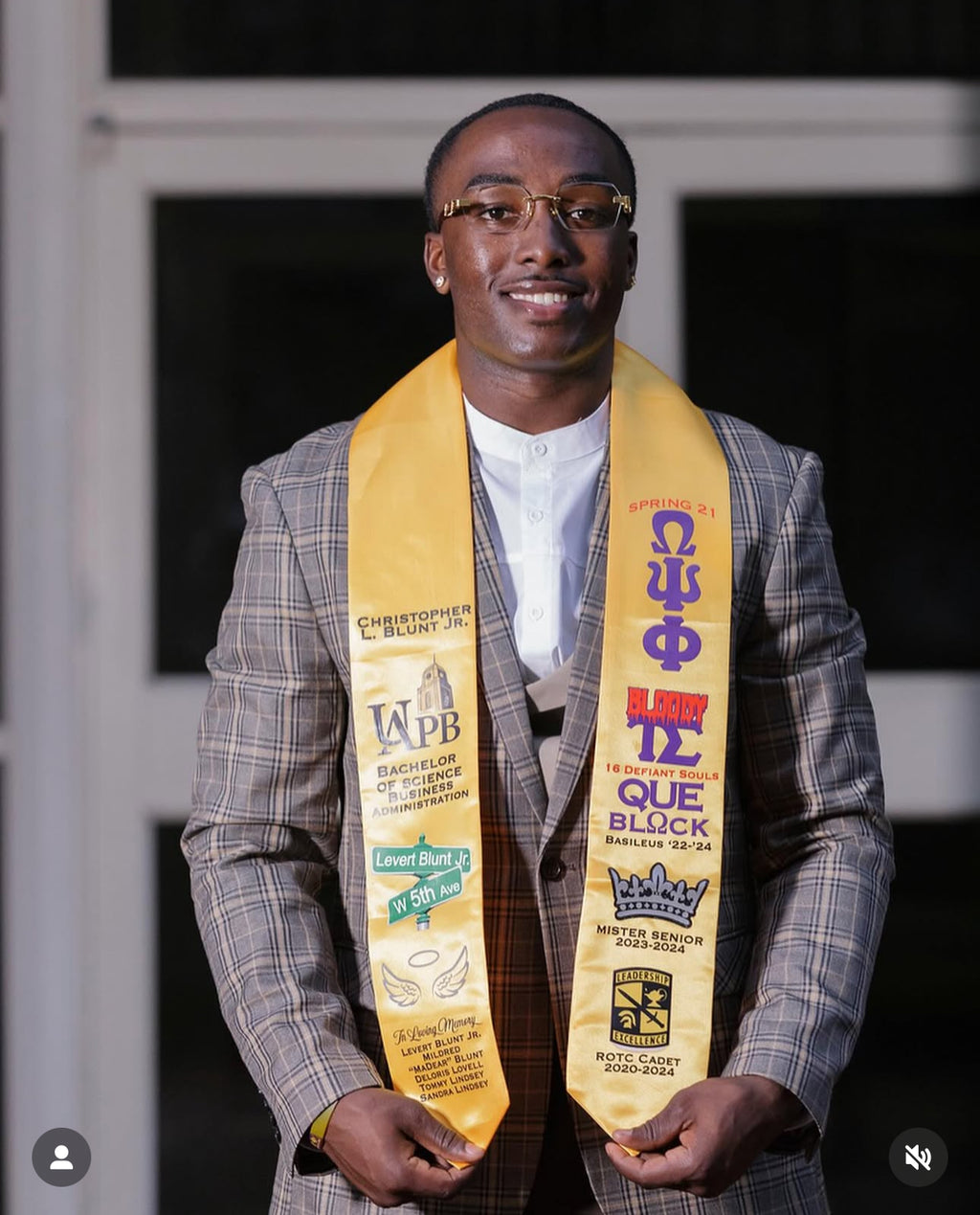Graduate wearing a yellow graduation stole with various logos and text